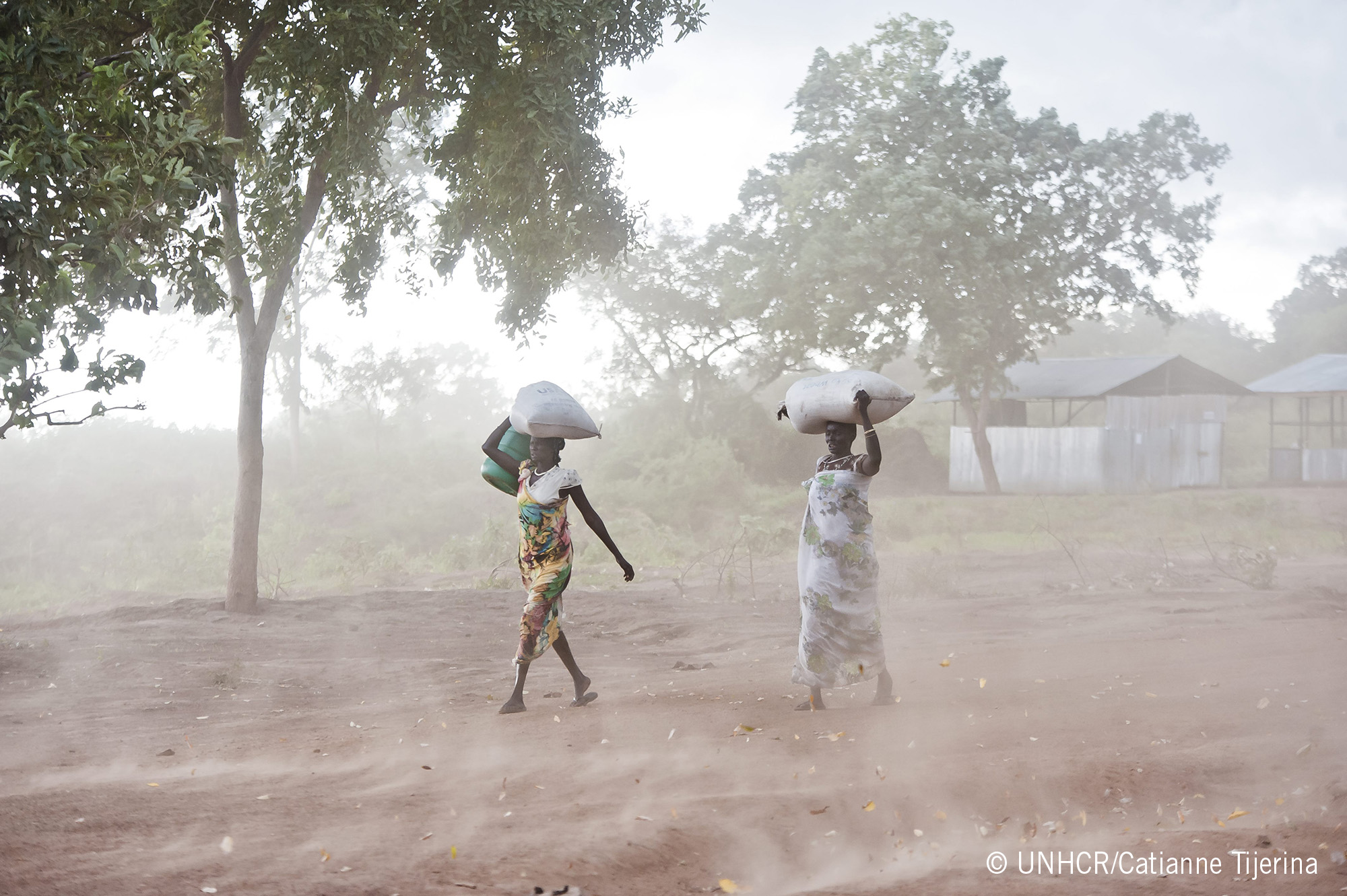 South Sudanese women rush through the rain at the Kule Refugee Camp in the Gambella Region of Ethiopia near the border. © UNHCR/Catianne Tijerina 2014